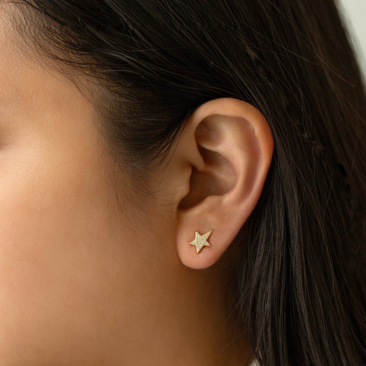Gold vermeil pavé star stud with white zirconia, shown close on a model's earlobe