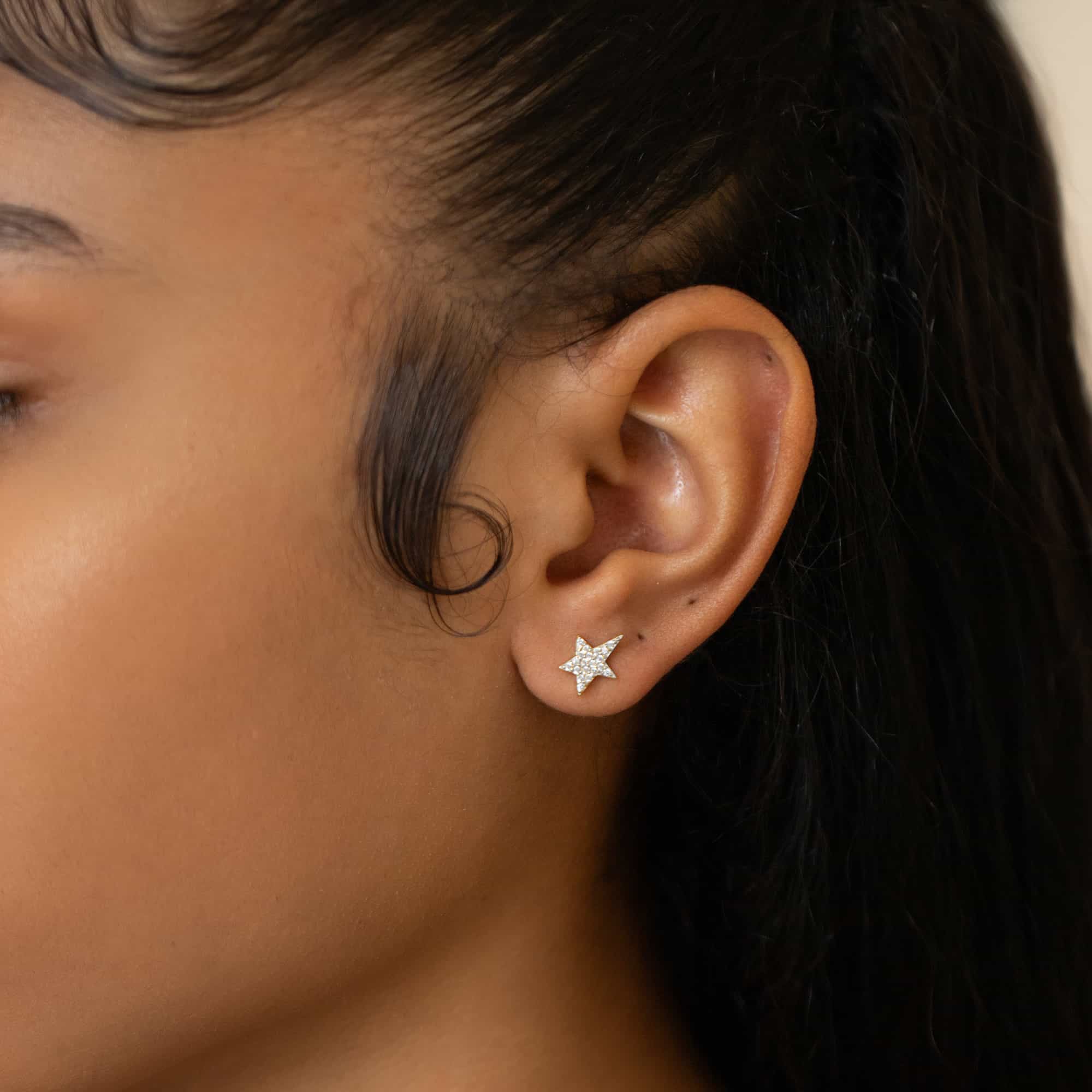Sterling silver pavé star stud with white zirconia, shown on a model's lower lobe