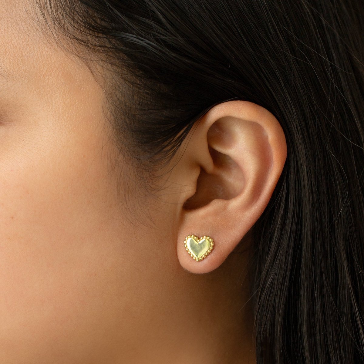 Gold vermeil beaded heart stud shown on a model's earlobe