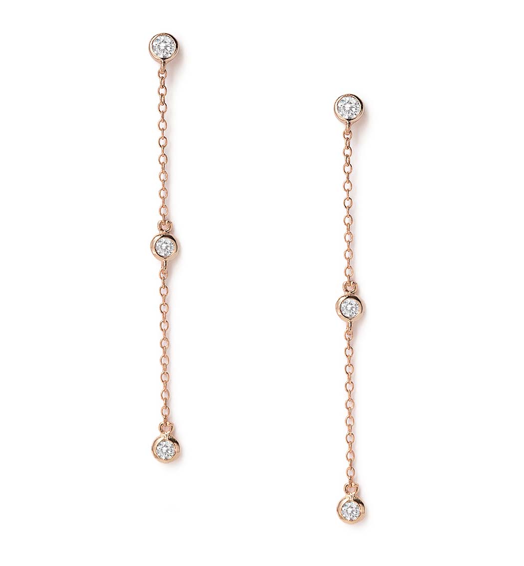 Rose gold vermeil drop earrings with three bezel-set round white zirconia stones on chain, on a white background