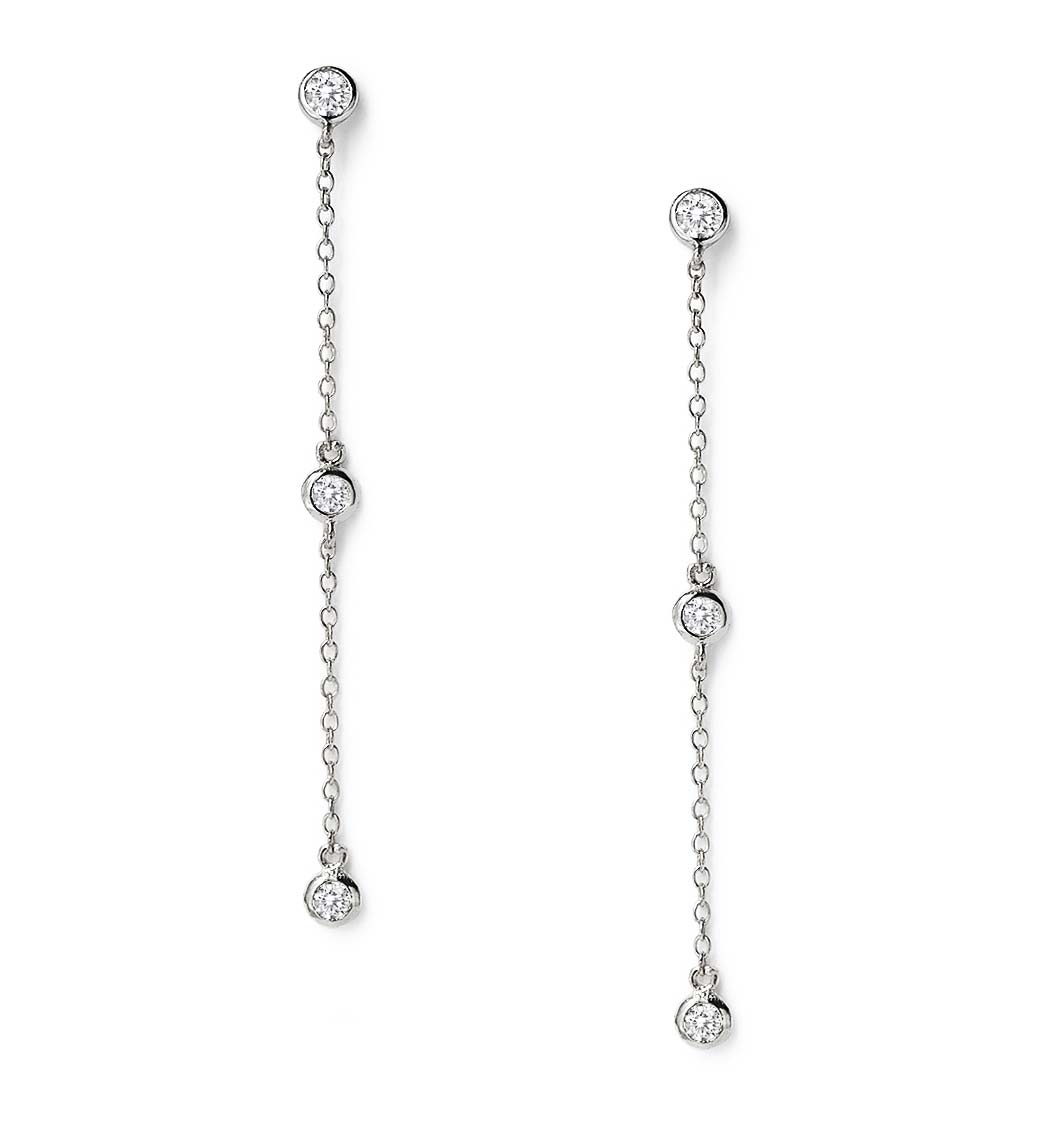 Sterling silver drop earrings with three bezel-set round white zirconia stones on chain, on a white background