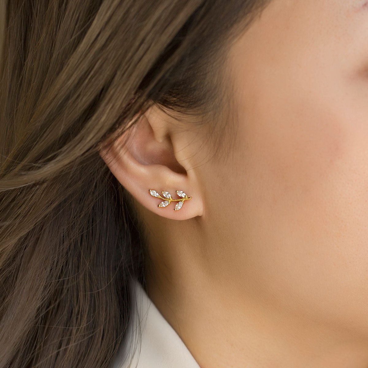 Gold vermeil leaf ear climber with marquise clear stones, shown close on a model's lobe