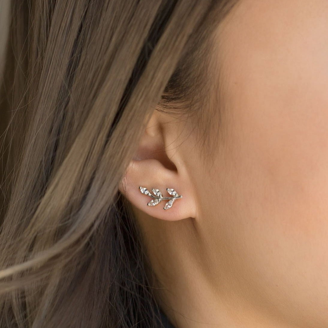 Sterling silver leaf ear climber with marquise clear stones, shown close on a model's lobe