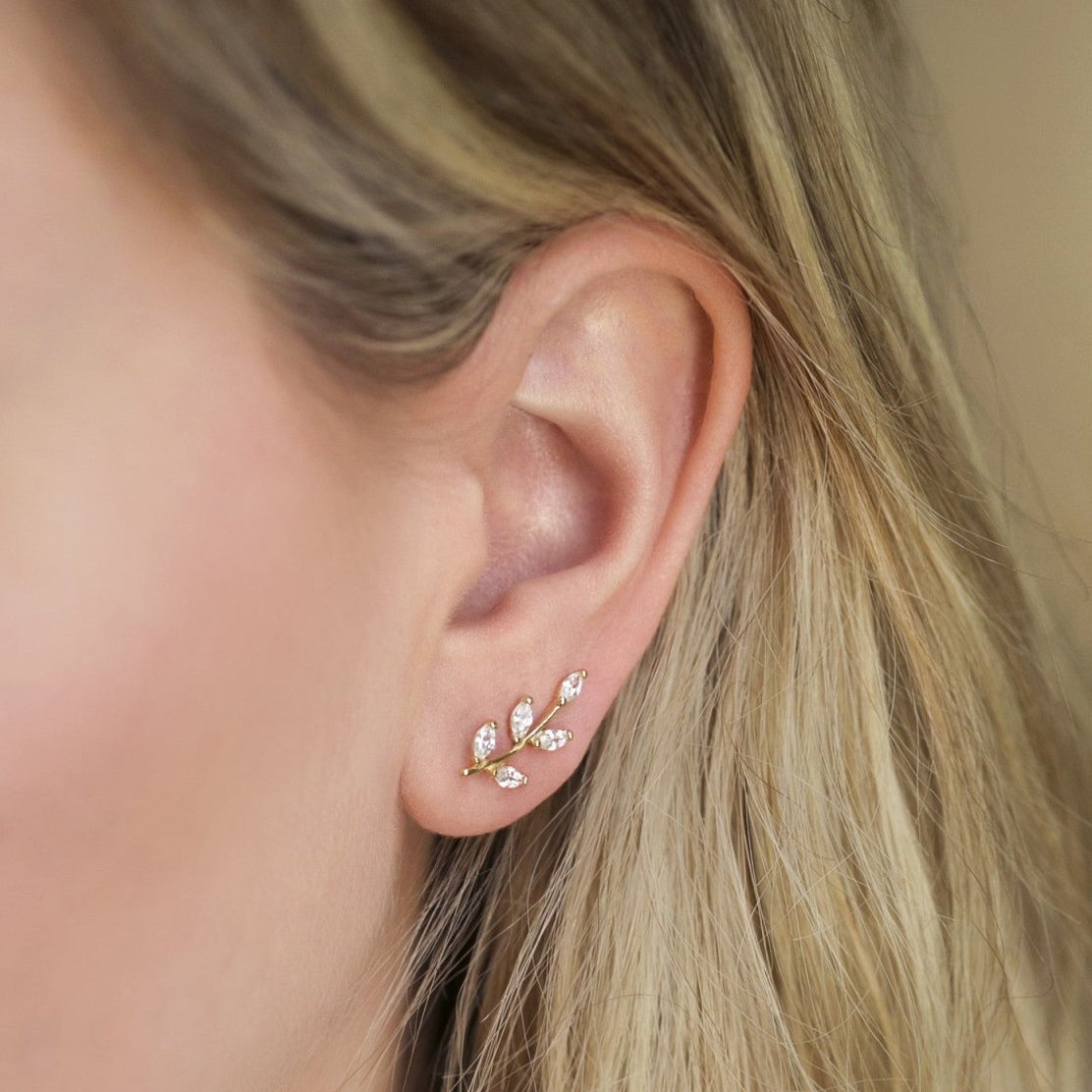 Gold vermeil leaf ear climber with clear stones, shown climbing up a model's lobe