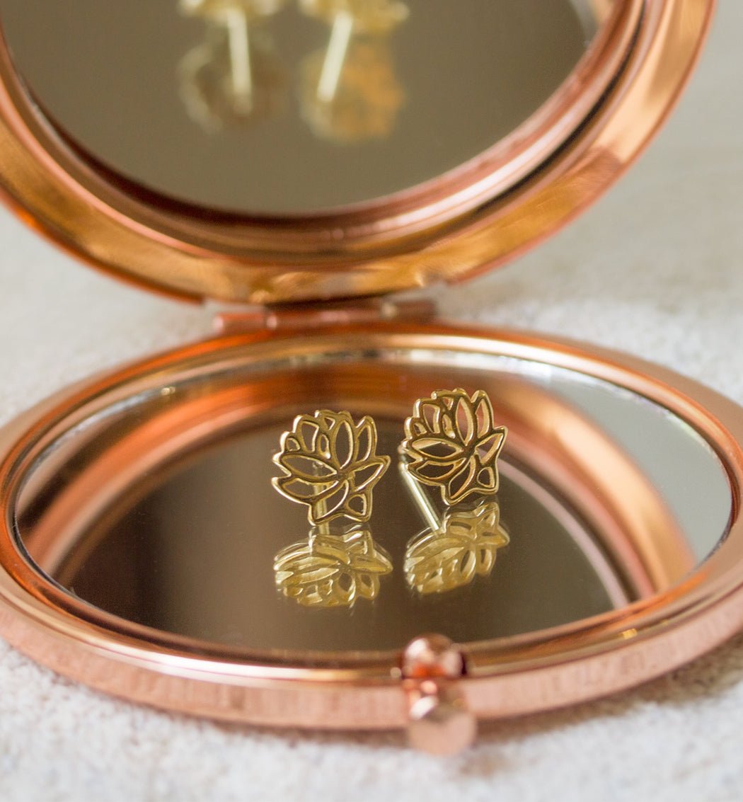 Gold vermeil lotus flower stud earrings reflected in a rose gold compact mirror