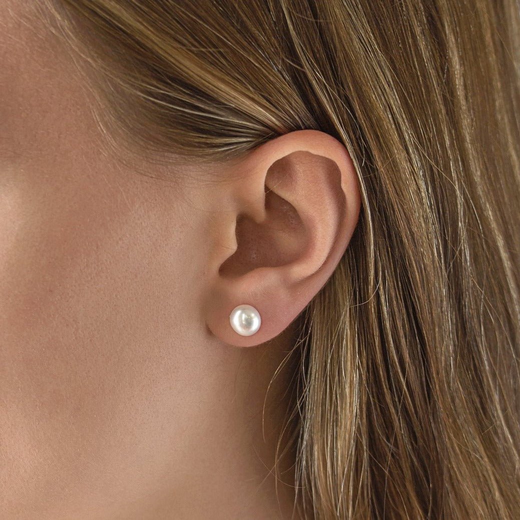 Sterling silver pearl stud earring with a round white pearl, shown on a model's lobe