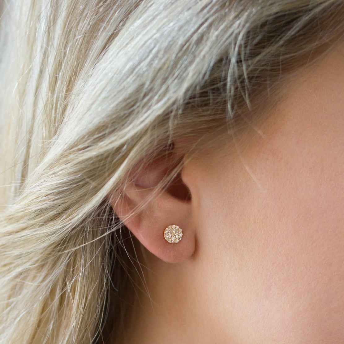 14K rose gold diamond pavé disc stud earring shown close up on a model's lobe