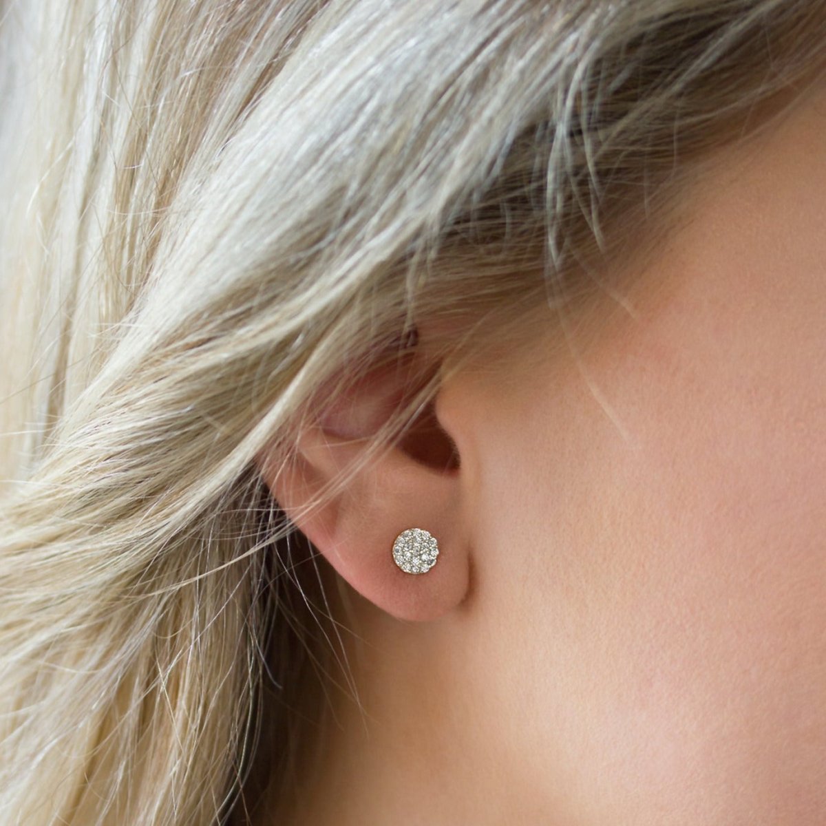 14K white gold diamond pavé disc stud earring shown close up on a model's lobe