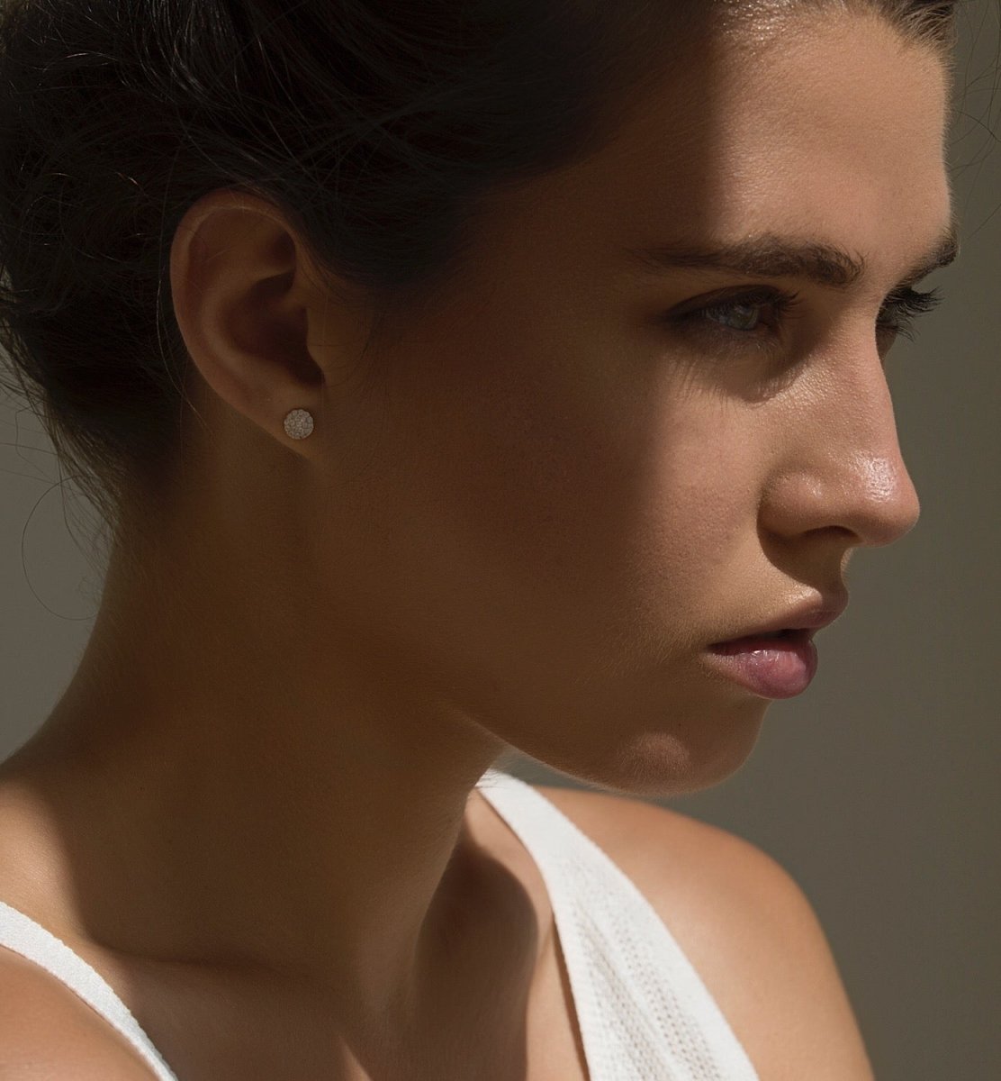 Sterling silver pavé round stud with white zirconia, shown on a model's lobe in profile