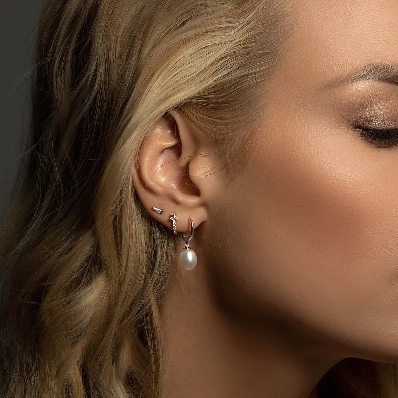 Sterling silver tapered baguette stud with white zirconia, shown on a model's lobe with a pearl drop hoop