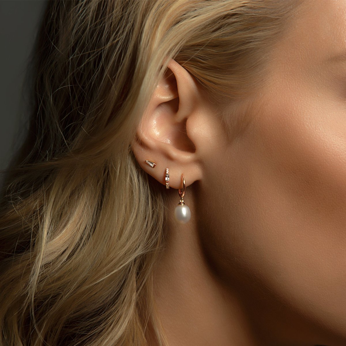 Rose gold vermeil tapered baguette stud with white zirconia, shown on a model's lobe with a pearl hoop