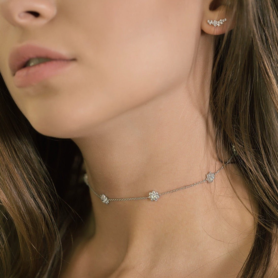 Sterling silver white zirconia choker with pavé flower stations, shown on a model's neck