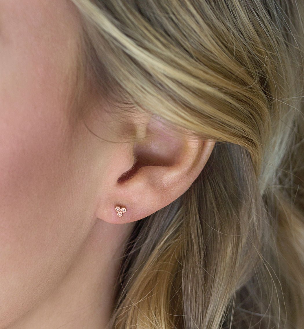 Rose gold vermeil bezel-set and prong-set zirconia trio studs, on cream fabric