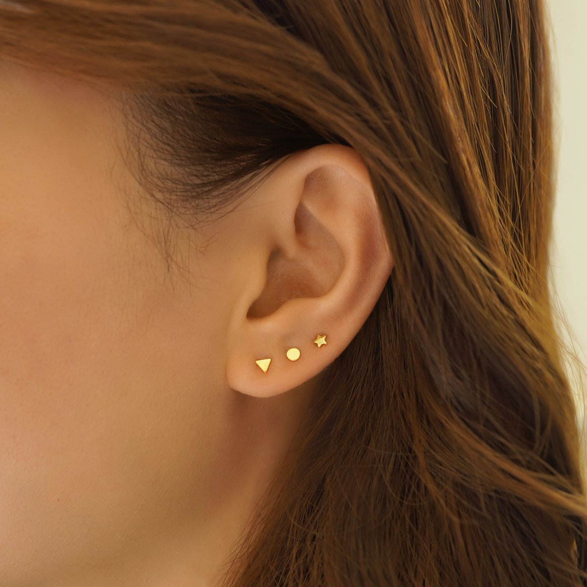 Gold vermeil tiny triangle, circle and star studs shown on a model's lobe
