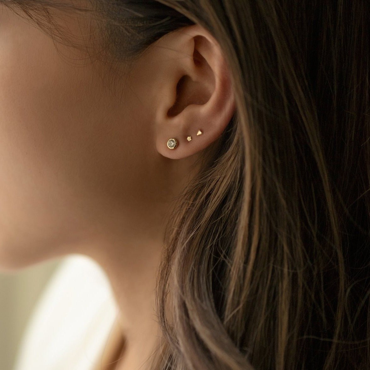 Rose gold vermeil tiny star stud shown on a model's ear in a stud and starburst stack