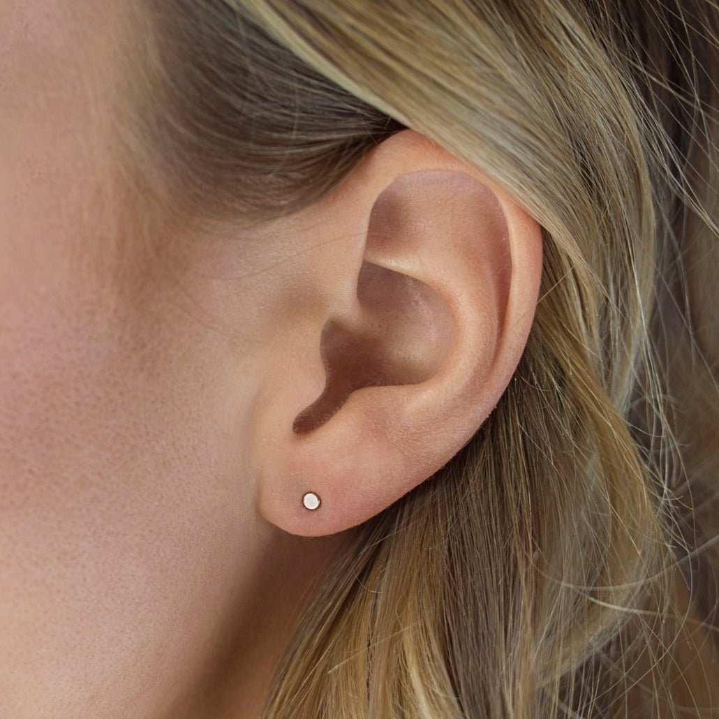 Sterling silver tiny circle stud shown on a model's lobe
