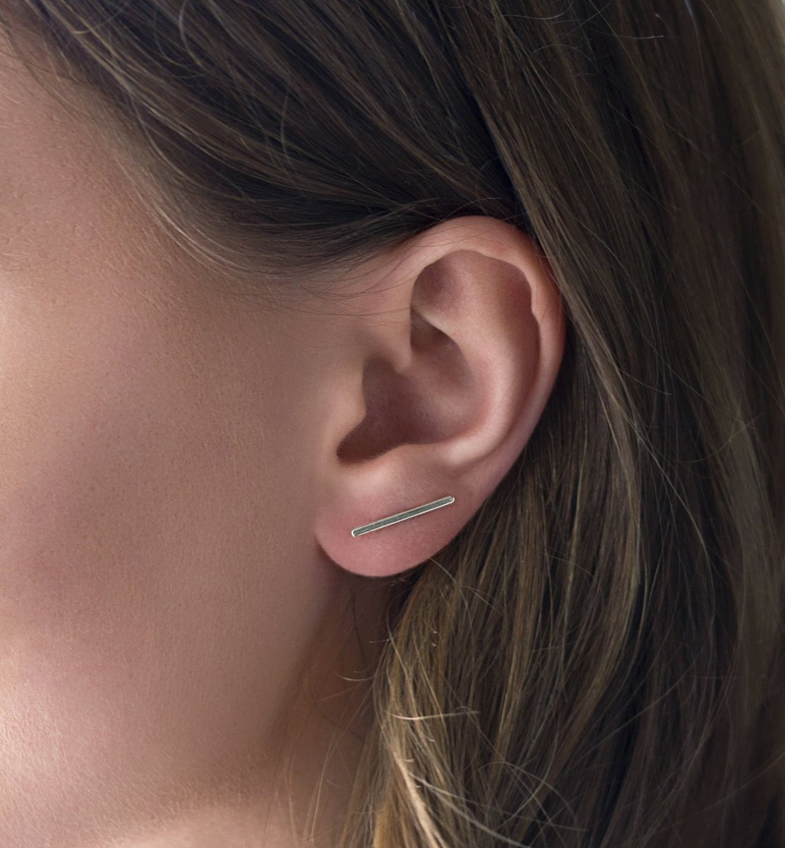 Sterling silver bar ear climber shown along the lower lobe on a model's ear