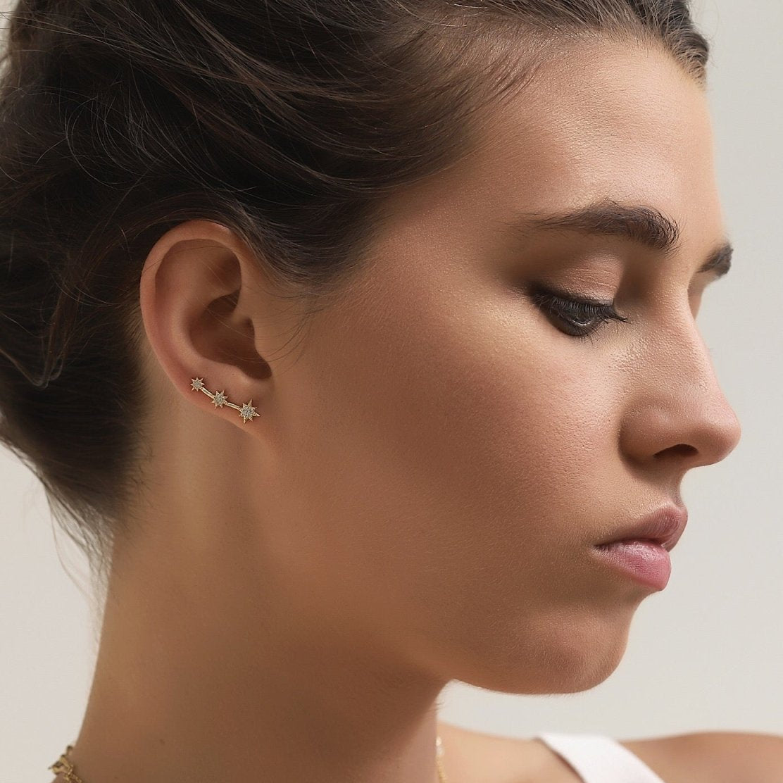 Gold vermeil three-star ear climber with white zirconia, shown climbing a model's lobe
