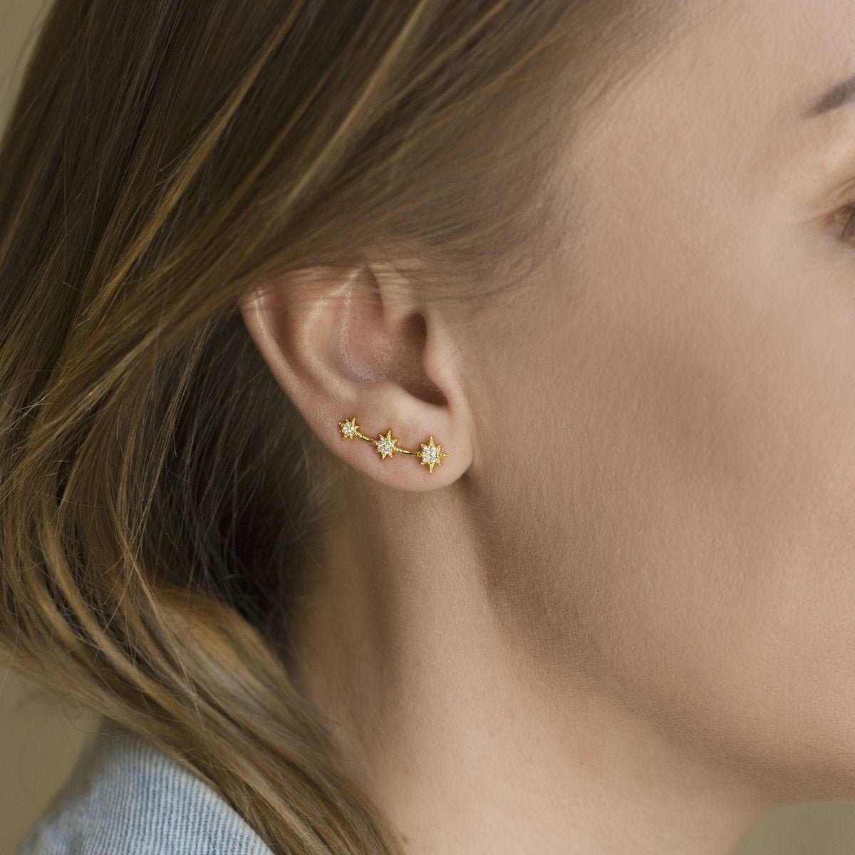 Gold vermeil three-star ear climber with white zirconia, shown on a model's ear from behind