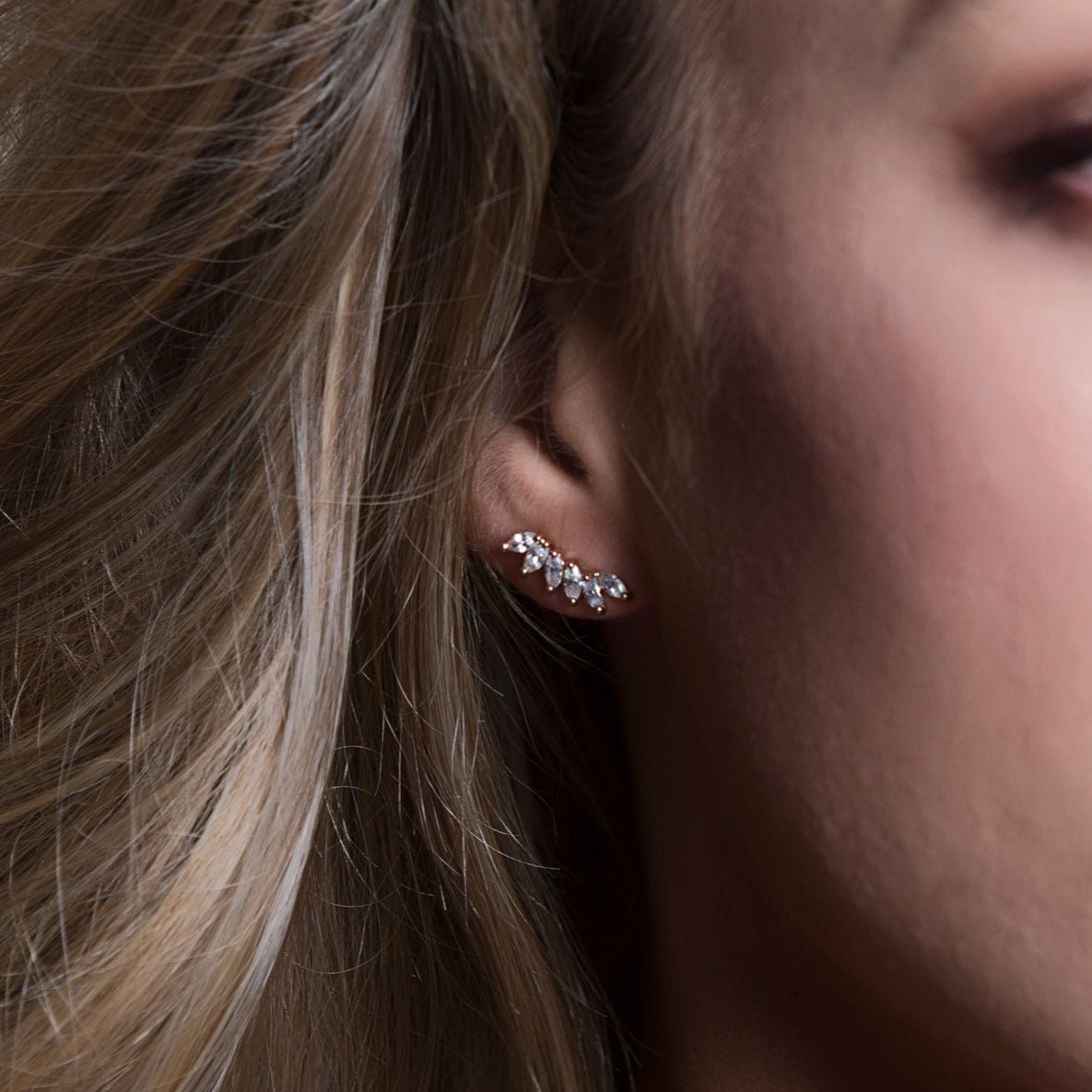 Rose gold vermeil wing climber with white zirconia stones, angled view on a model's lobe and helix