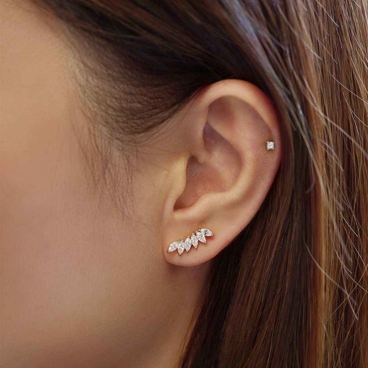 Sterling silver climber earring with white zirconia marquise stones, shown on a model's lobe and helix