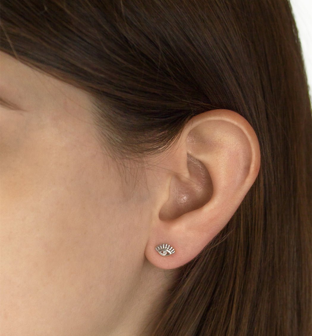 Sterling silver evil eye stud with a clear center stone, shown on a model's lobe