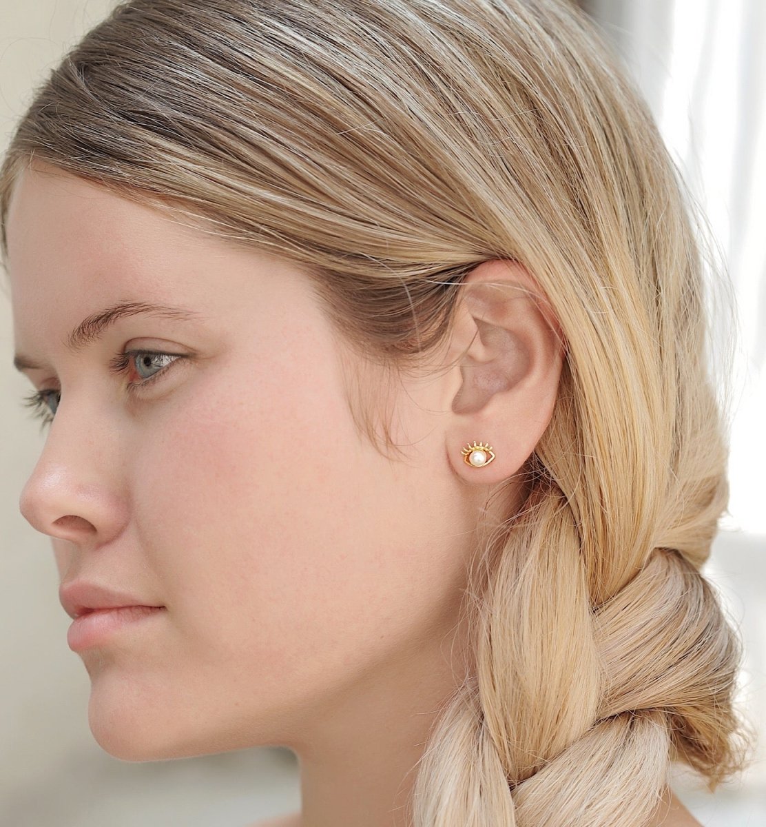 Gold vermeil evil eye pearl stud earring shown on a model's lobe