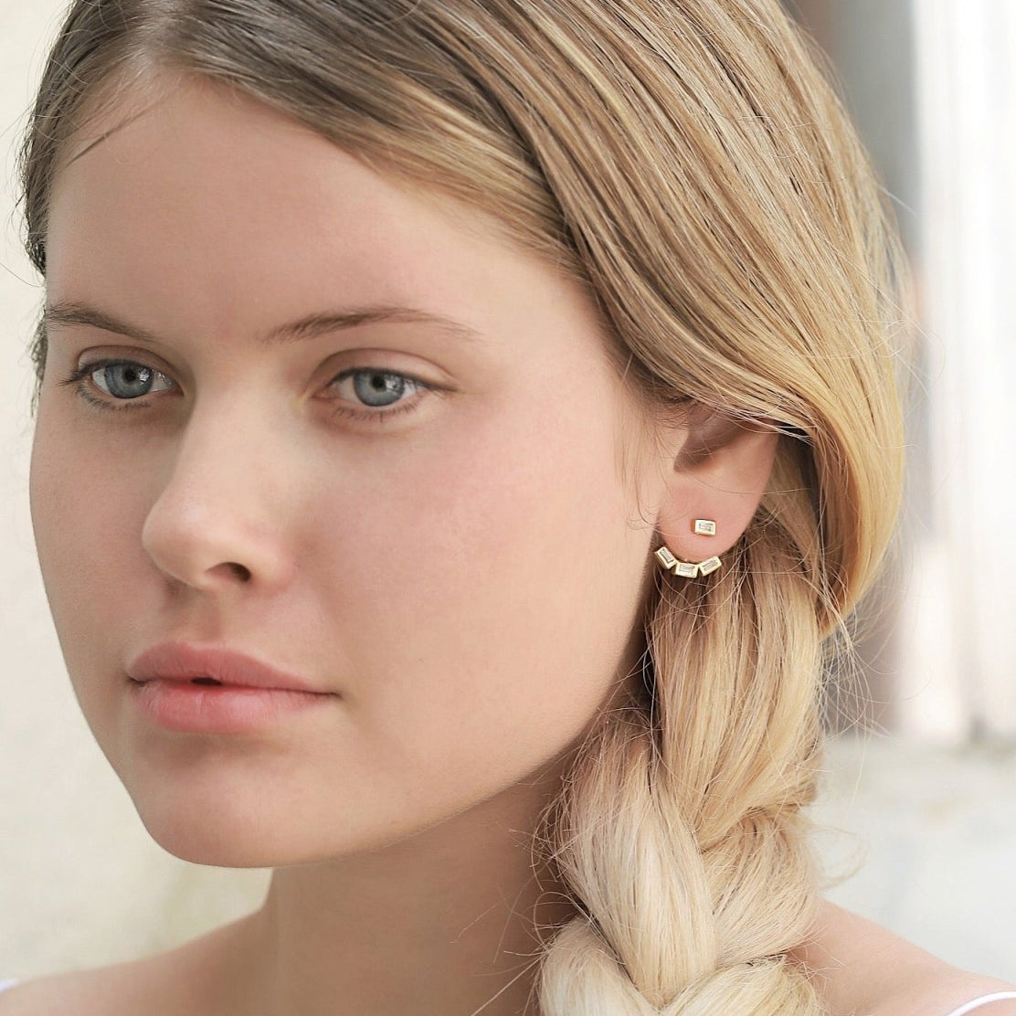 Rose gold vermeil baguette ear jacket with clear stones on a blonde model's lobe, front view