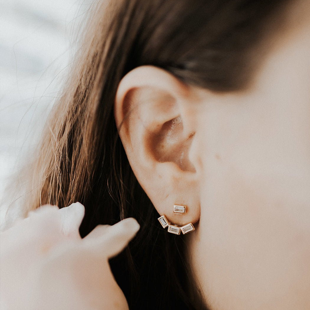 Sterling silver baguette ear jacket earrings with clear stones, gold finish, on a white background
