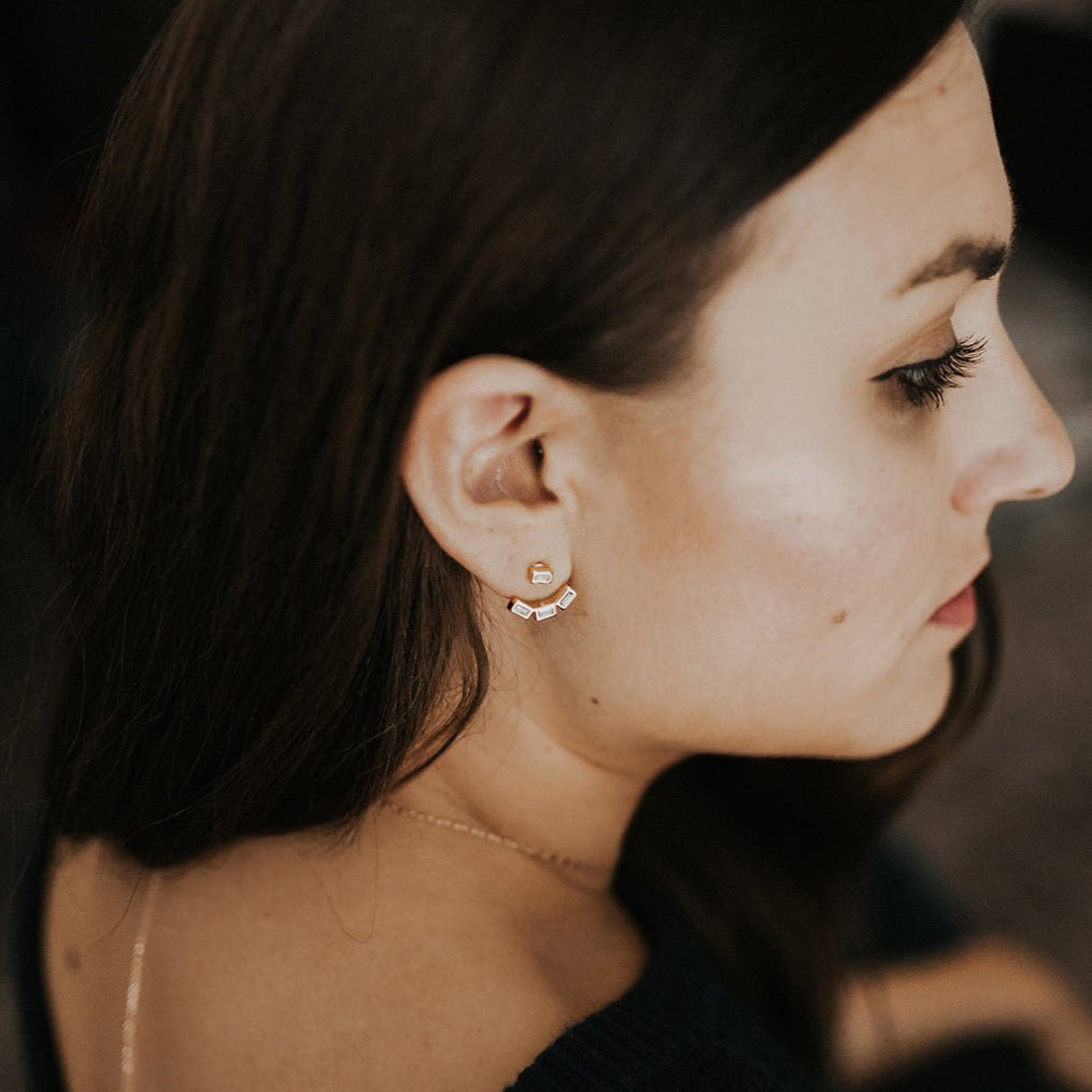 Rose gold vermeil baguette ear jacket with clear stones worn on a model's lobe, profile view