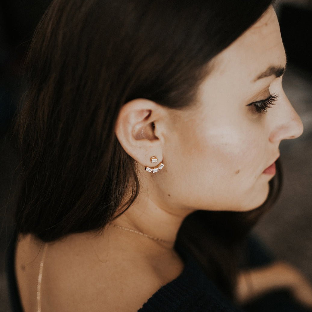 Sterling silver baguette ear jacket with clear stones worn on a model's lobe, profile view
