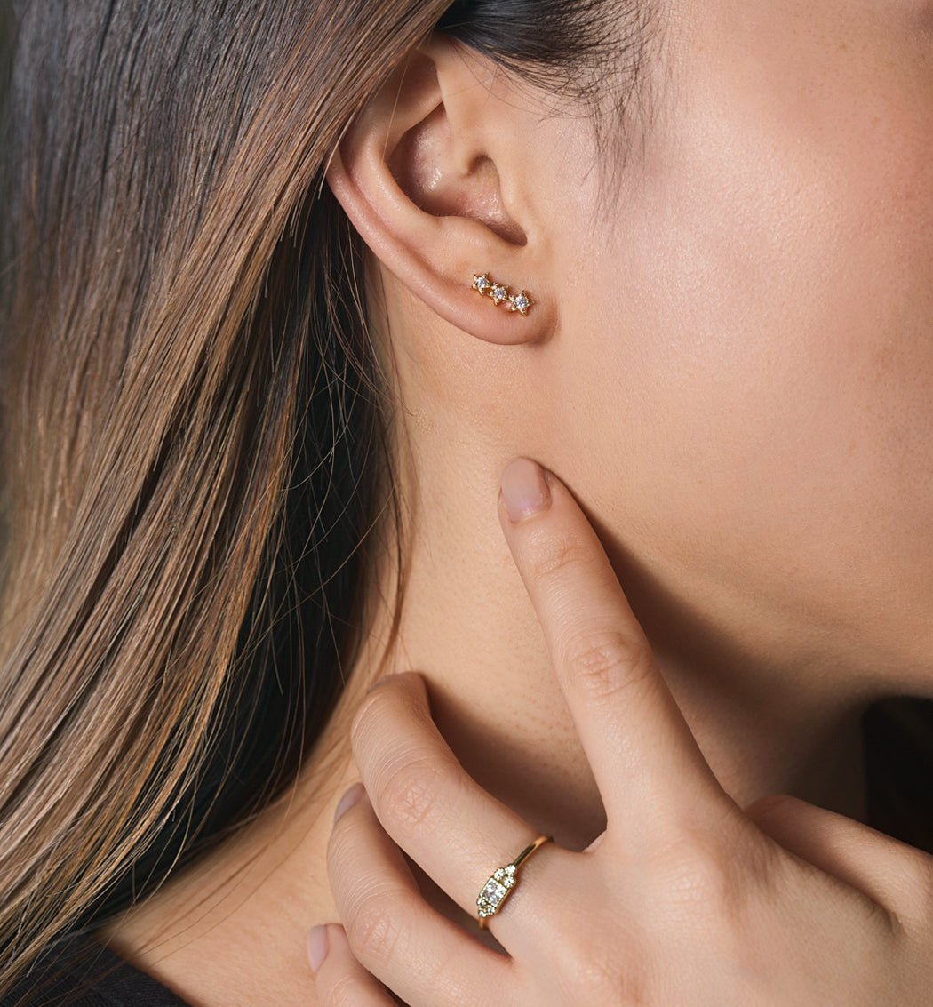 Sterling silver three-star dainty studs with clear stones, shown on a model's ear