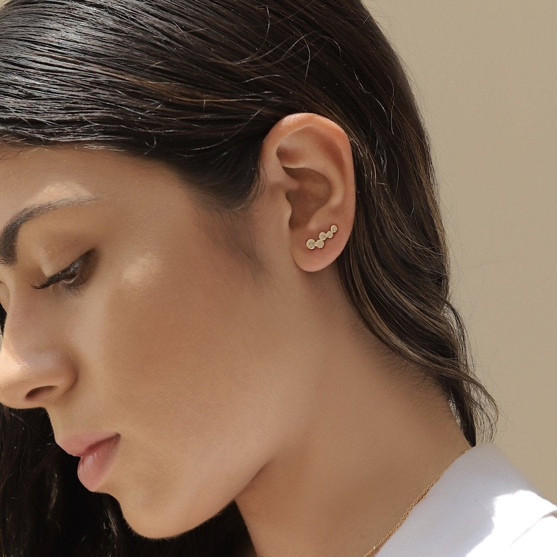 Gold vermeil bezel-set crystal ear climber shown curving up a model's earlobe