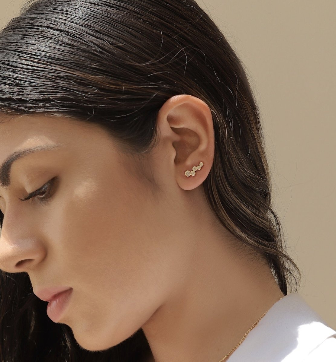 Sterling silver bezel-set crystal ear climber shown curving up a model's earlobe