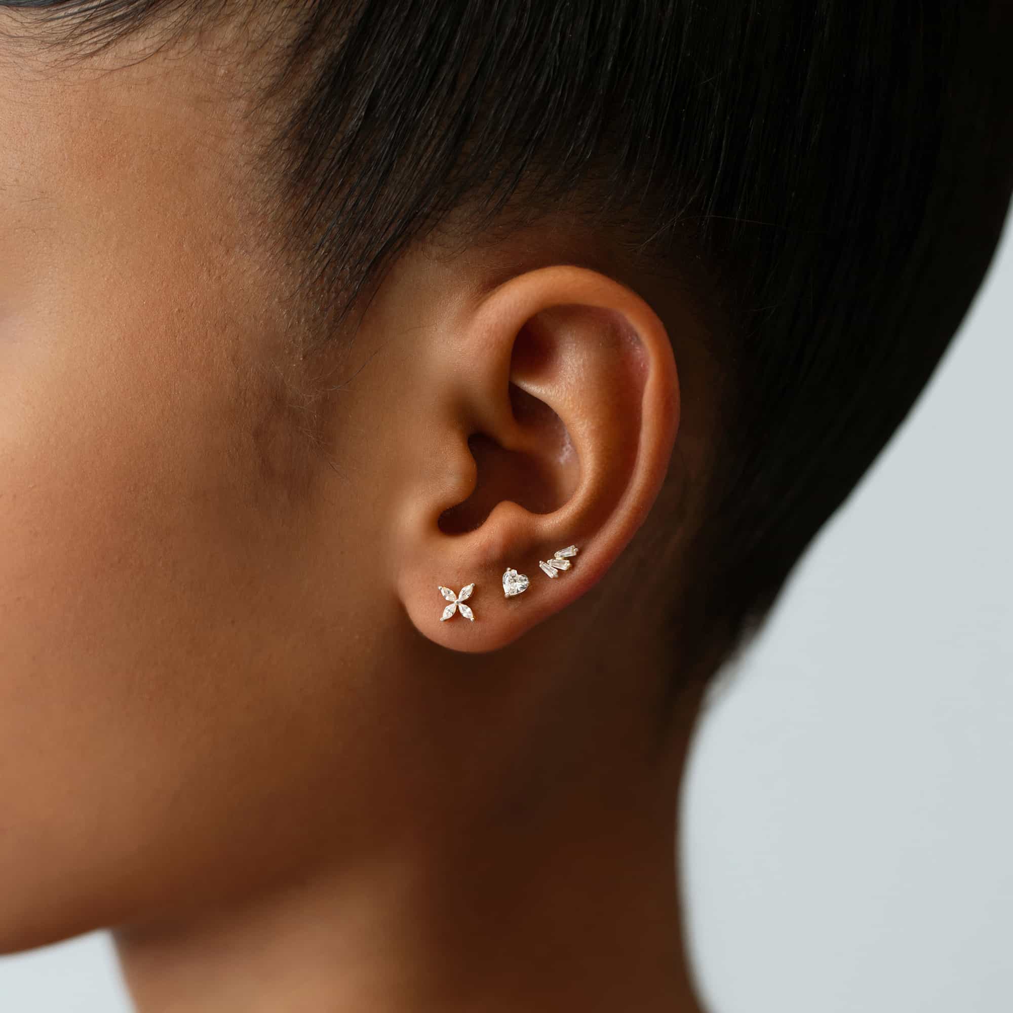 Sterling silver crystal flower stud shown in a stack on a model's earlobe