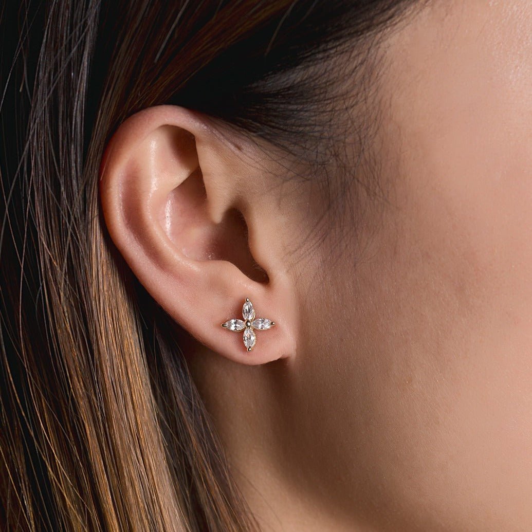 Rose gold vermeil four-petal crystal flower stud shown on a model's earlobe