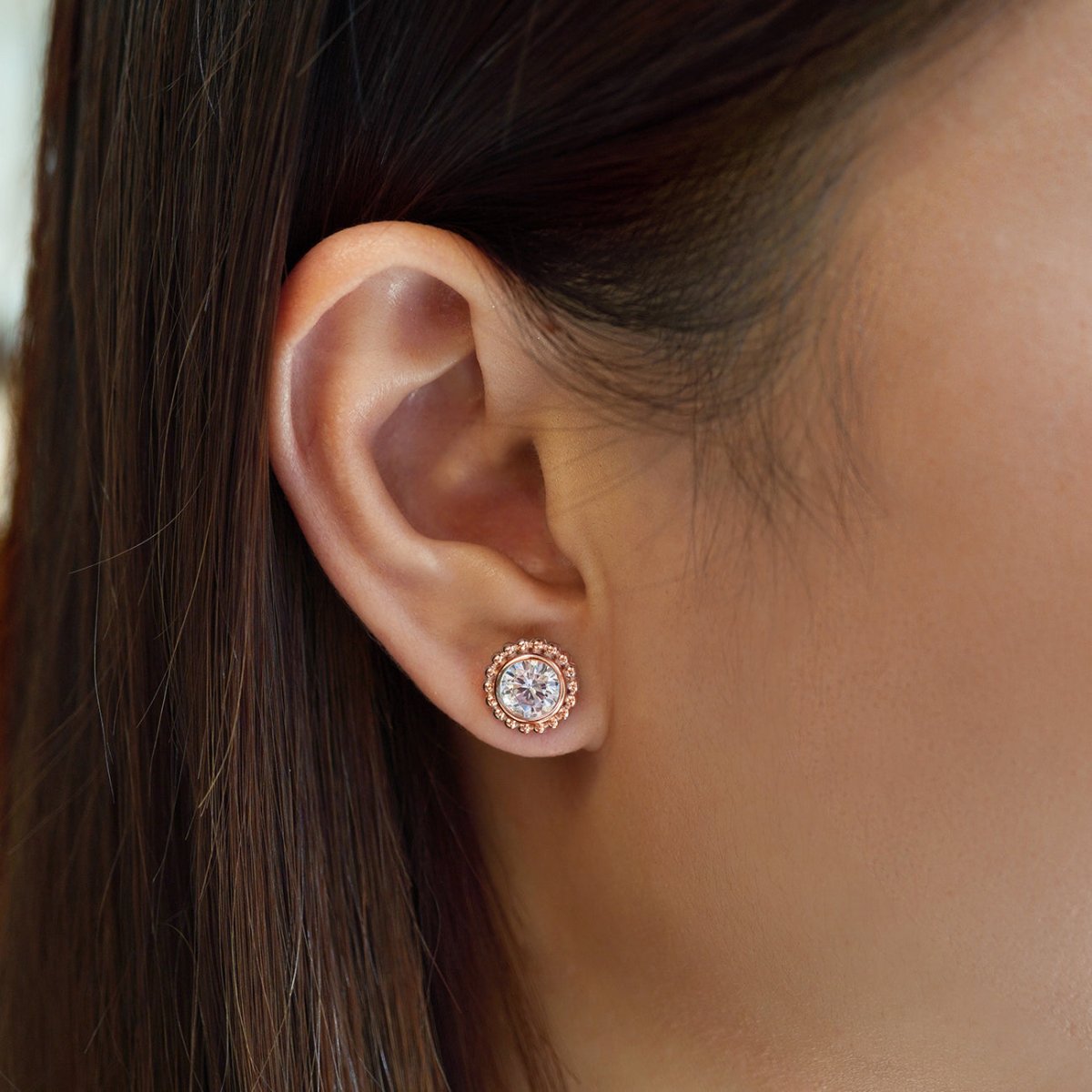 Rose gold vermeil beaded halo stud with a clear stone shown on a model's lobe