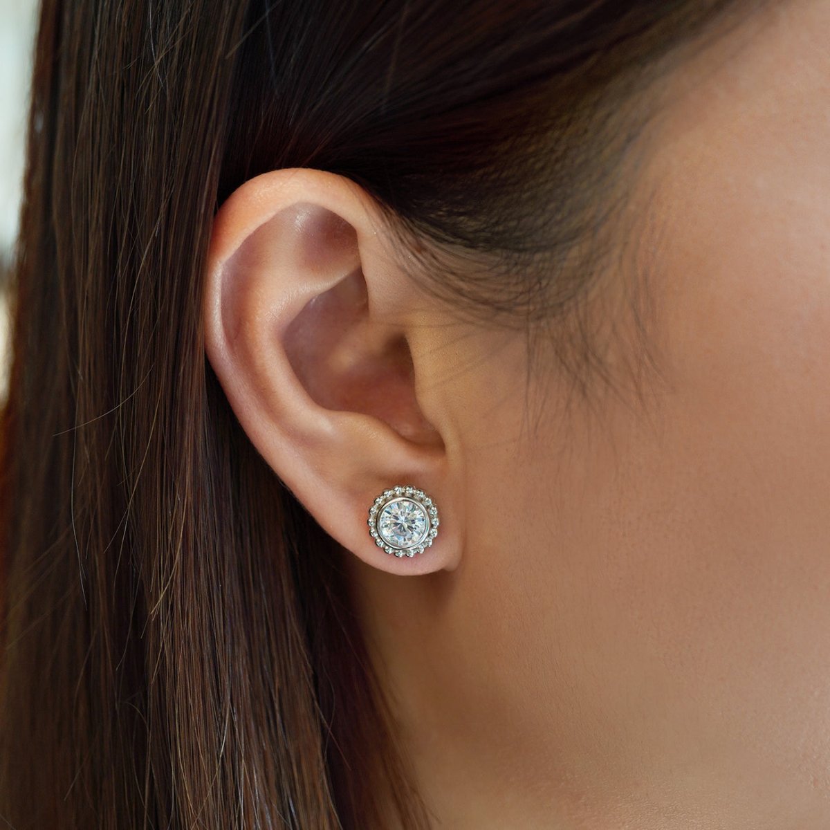 Sterling silver halo stud with a round clear stone and beaded crystal frame, shown on a model's lobe