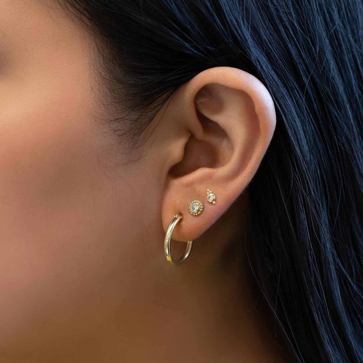 Gold vermeil beaded white zirconia studs shown with a hoop in an ear stack on a model