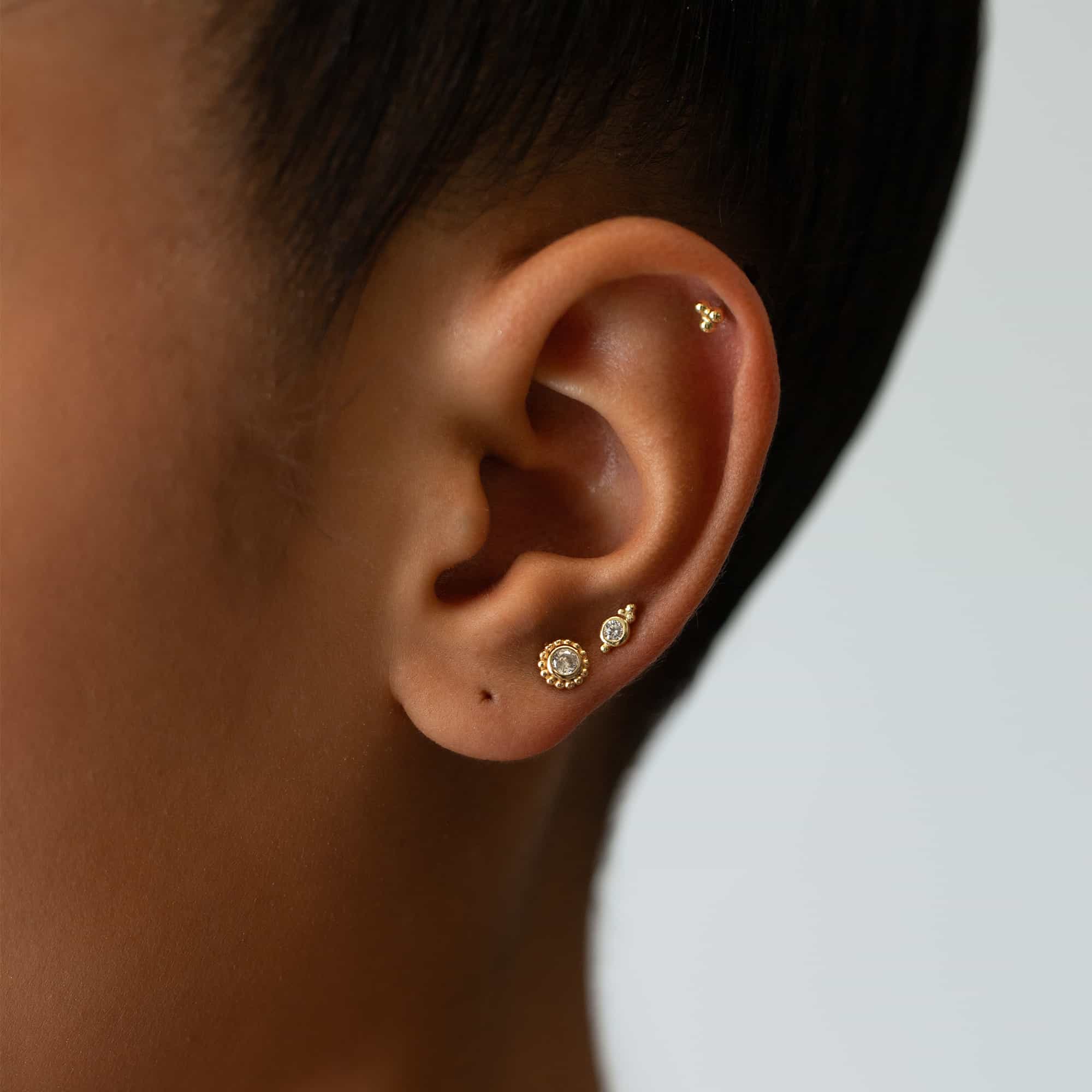 Gold vermeil beaded studs with white zirconia stones, styled in an ear stack on a model