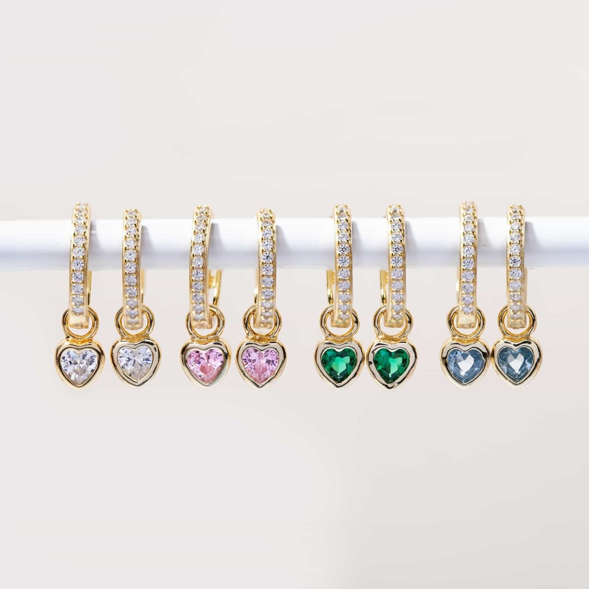 Gold vermeil pavé huggie hoops with heart charms in clear, pink, green and blue stones, in a row