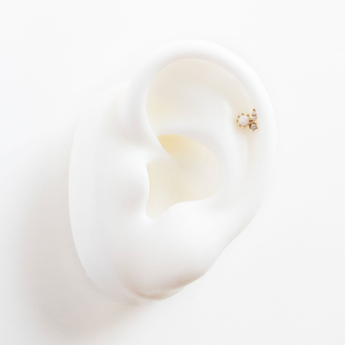 Gold vermeil white opal cluster stud with clear stones shown on a model's helix