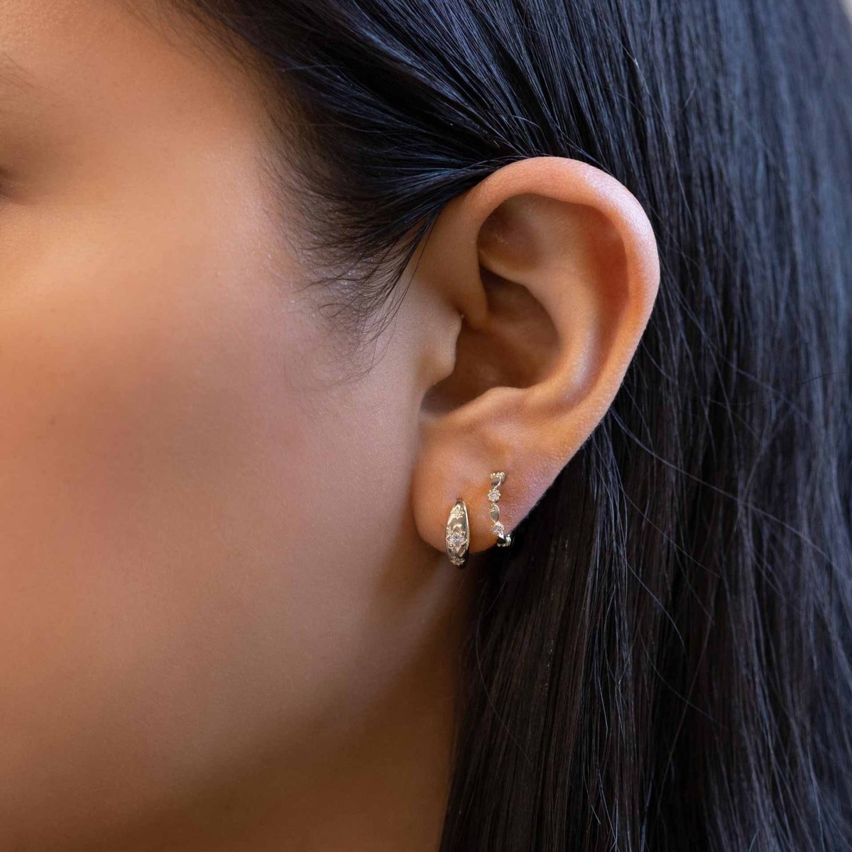 Sterling silver ornate C hoop with white zirconia stones, shown close-up on a model's lobe