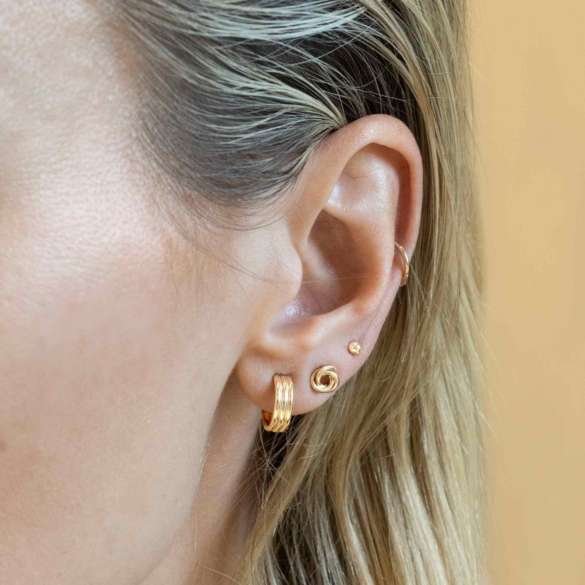 Gold-filled ridge huggie hoop shown on a model's lobe in a stacked ear setup