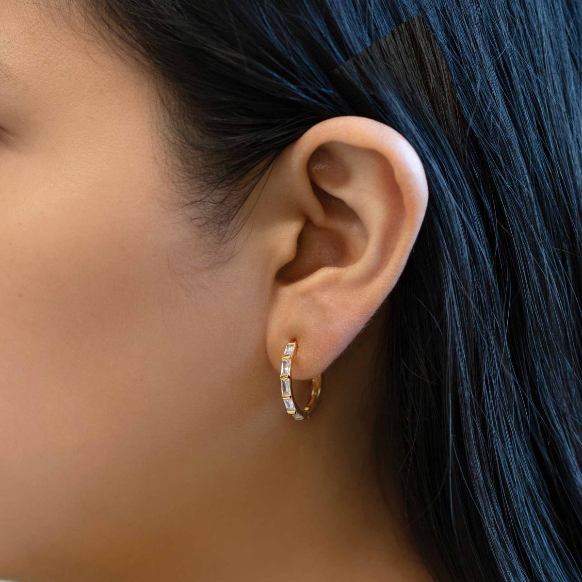 Gold vermeil baguette statement hoop with clear zirconia shown on a model's lobe