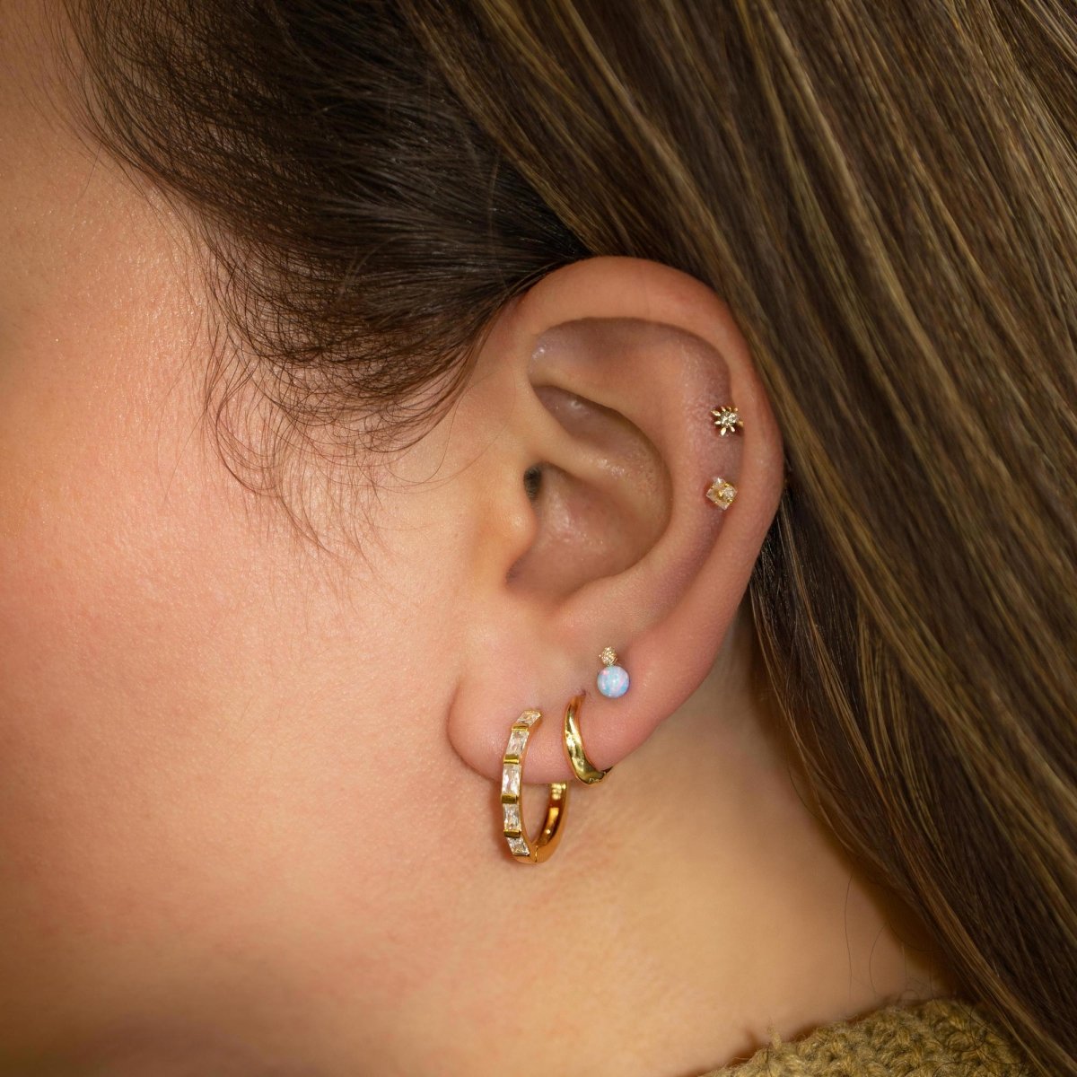 Gold vermeil baguette statement hoop with clear zirconia stones shown stacked on a model's lobe