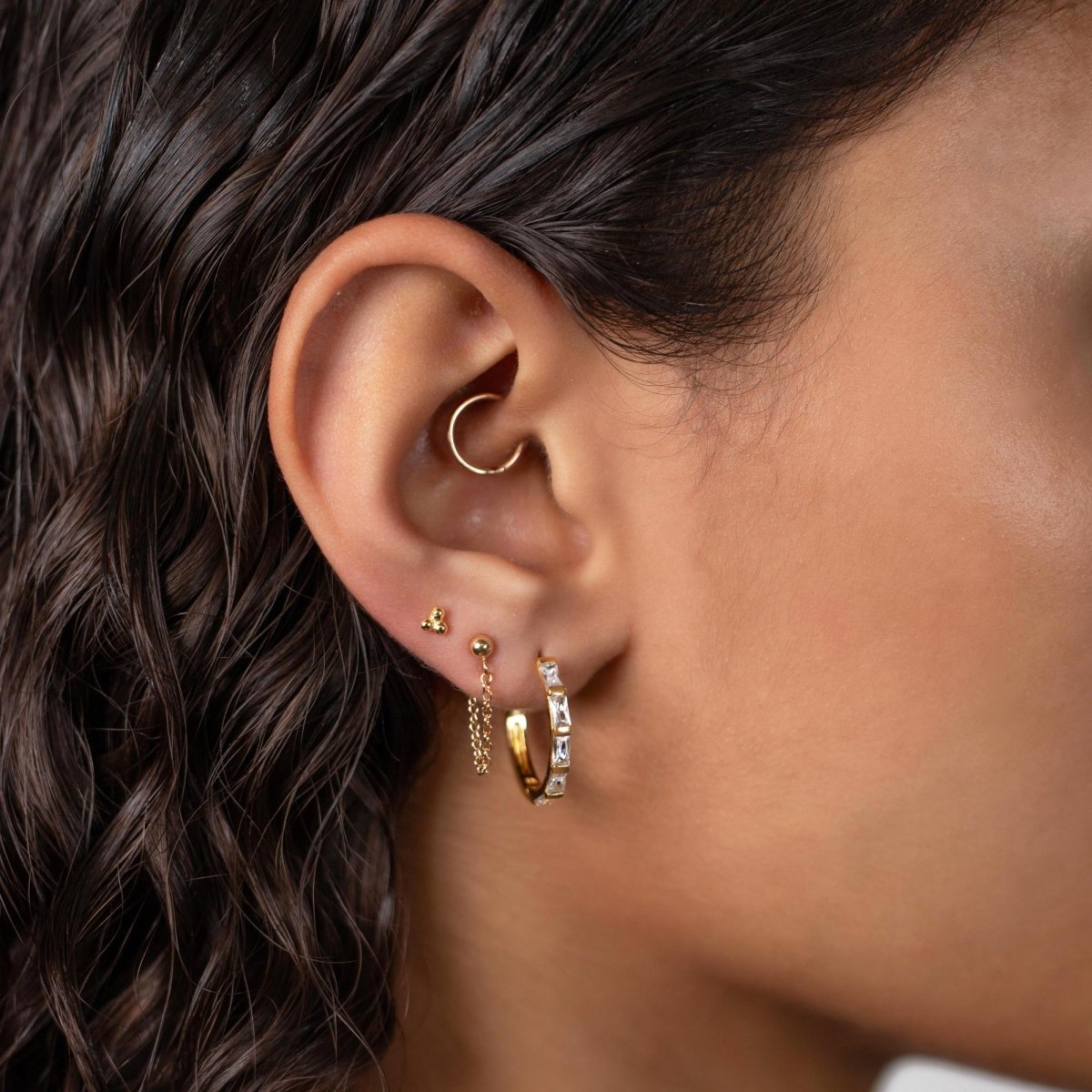 Gold vermeil baguette statement hoop with clear zirconia shown on a model's lobe