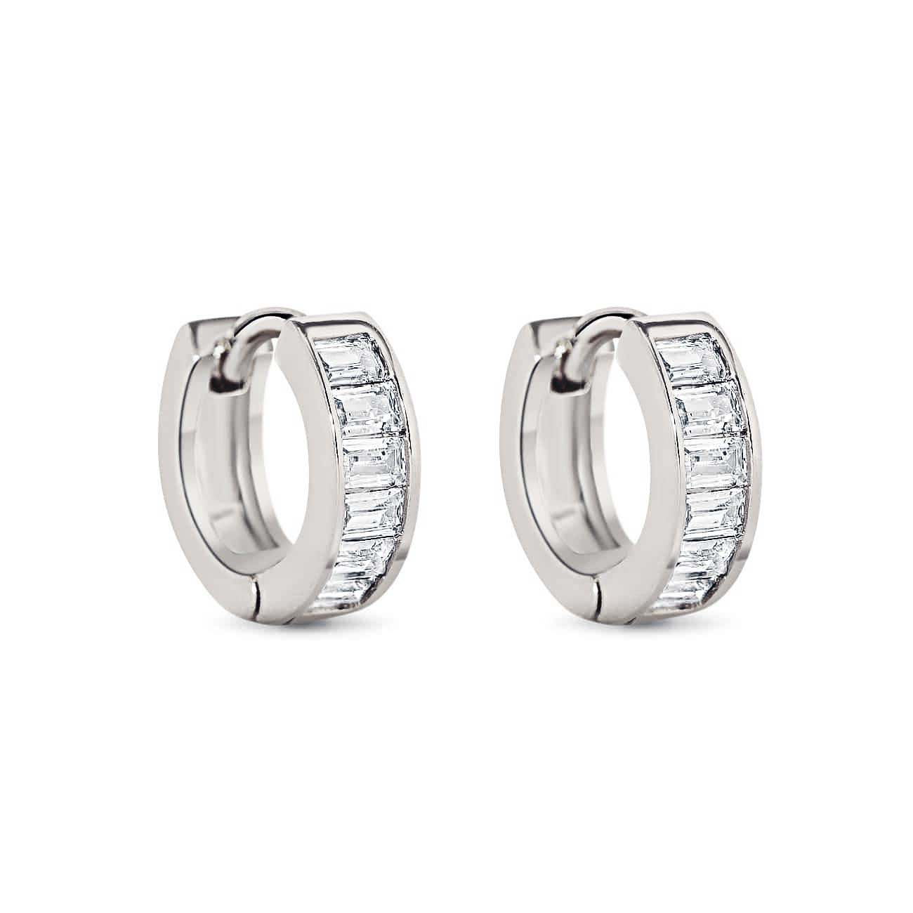 Pair of sterling silver huggie hoops with channel-set clear baguette stones, on a white background