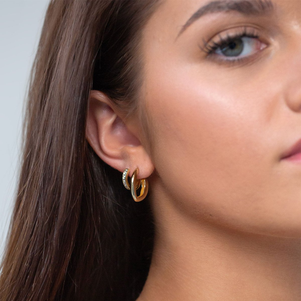 Gold vermeil sculptural mini hoop layered with a pavé huggie, shown on a model's lobe