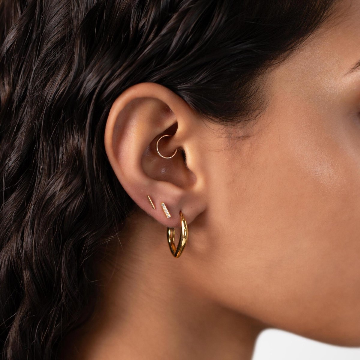 14K gold pave bar studs styled with two plain gold bar studs in a stack, shown on a model's ear
